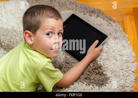 Kleiner Junge am Boden liegend und mit digital-Tablette Stockfoto