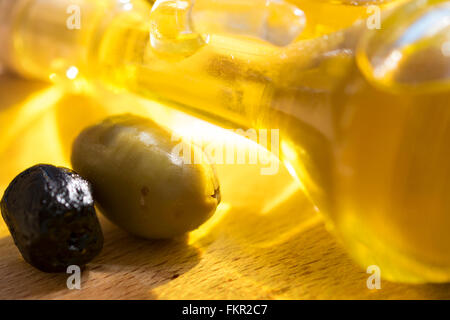 Olivenölflasche mit einigen Oliven Stockfoto