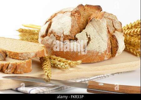 Nahaufnahme von frisch gebackenem Brot, Küchenmesser und Reife Ähren auf Holzbrett Stockfoto