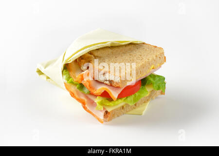 frisches Sandwich mit Schinken, Käse und Gemüse eingewickelt in Papierserviette Stockfoto