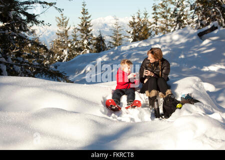 Kaukasische Mutter und Sohn trinken heißen Kakao im Schnee Stockfoto