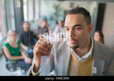 Geschäftsmann Zeichnung Grafik Glaswand im Büro Stockfoto