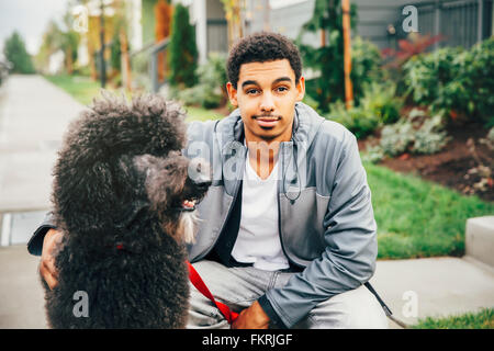 Gemischte Rassen Mann Petting Hund auf Bürgersteig Stockfoto