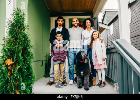 Familie und Hund lächelnd auf Terrasse Stockfoto