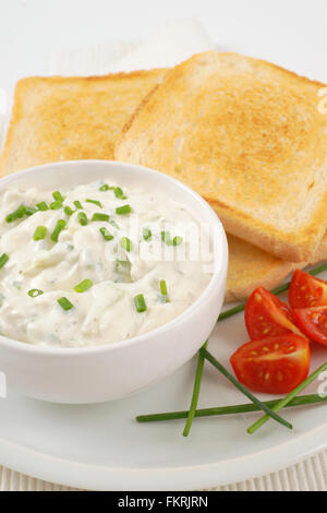 Nahaufnahme von frischem Toast und Schüssel mit Schnittlauch auf weißen Teller verteilen Stockfoto