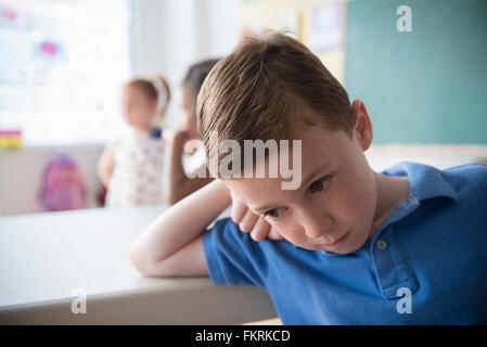 Traurig Student stützte sich auf Schreibtisch Stockfoto