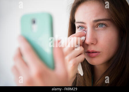 Indianer Frau mit Handy, die Tränen abwischen Stockfoto