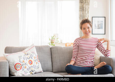 Gemischte Rassen Frau sitzend auf sofa Stockfoto