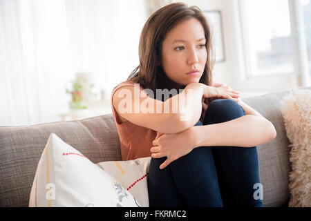 Trauriges gemischte Rasse Frau sitzend auf sofa Stockfoto