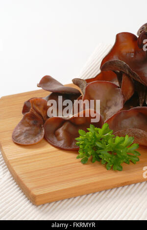 Nahaufnahme von gekochten Ohr Pilze auf Holzbrett und weißen Tischset Stockfoto
