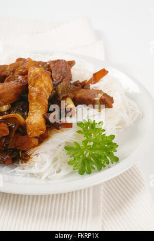 Teller mit gebratenem Fleisch, Ohr Pilze und Reisnudeln auf weißen Tischset Stockfoto