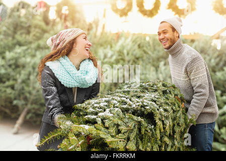 Paar schleppen Baum auf Christmas Tree farm Stockfoto