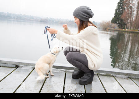 Japanische Frau zu Fuß Hund in der Nähe von See Stockfoto