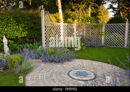 Mosaik, Pflasterarbeiten, blühende Pflanzen, Skulpturen und Rankgitter in sonnigen, gestaltete, gepflegte, Garten, Burley in Wharfedale, Yorkshire, England. Stockfoto