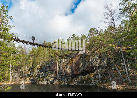 Trekker Überquerung einer Hängebrücke in Repovesi Nationalpark, Finnland. Stockfoto