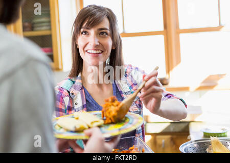 Hispanic Frau Portion Freund in der Küche Stockfoto