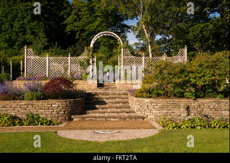 Sunlit Pflanzen & Sträucher Steinmauer, Schritte, rankgitter Arch und Bildschirm - schön gestaltet, gepflegten, privaten, terrassenförmig angelegten Garten - Yorkshire, England, UK. Stockfoto