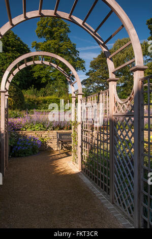 Blick entlang eines Tunnels Laube zu blühenden Pflanzen auf dem angehobenen Grenze - schön gestaltet & gepflegten, traditionellen Garten - West Yorkshire, England, UK. Stockfoto