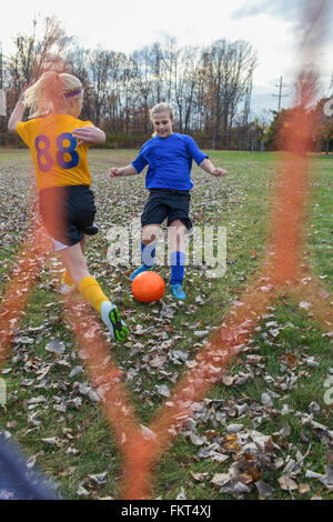 Kaukasische Mädchen spielen Fußball im Feld Stockfoto