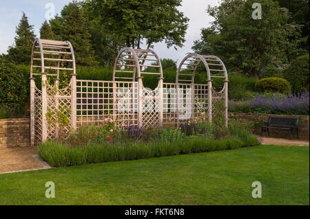 Tunnel-Laube und krautige Grenze im gestaltete, gepflegte, traditionelle Garten, Burley in Wharfedale, West Yorkshire, England - im Sommer. Stockfoto
