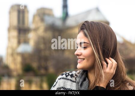 Seitenansicht der jungen Frau, die Kathedrale Notre-Dame im Hintergrund, Paris, Frankreich Stockfoto