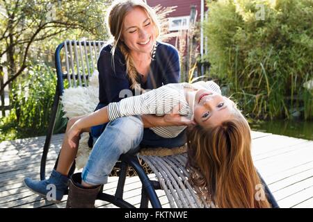 Mädchen sitzen auf Mutters Schoß, lehnt sich zurück Stockfoto