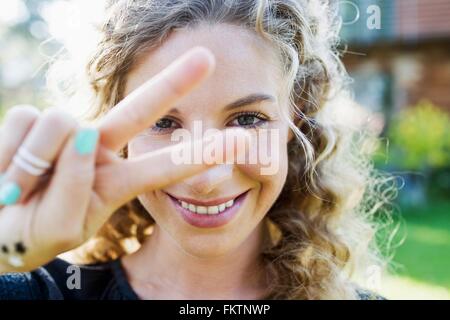 Junge Frau, die Peace-Zeichen mit der Hand machen Stockfoto