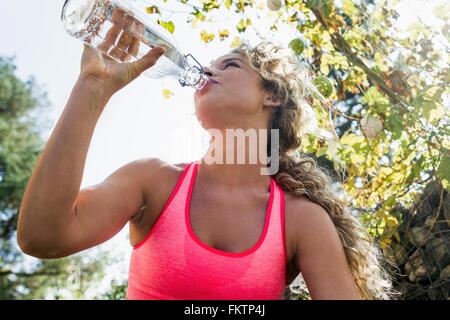 Junge Frau Trinkwasser aus der Flasche Stockfoto