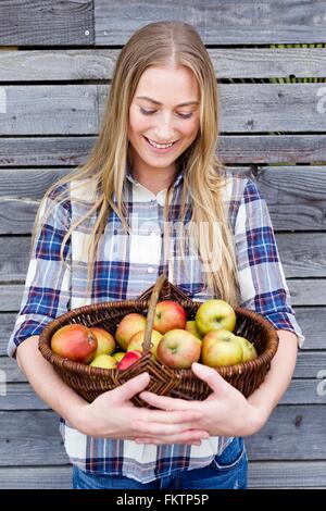 Mitte Erwachsene Frau hält Korb einheimische Äpfel Stockfoto
