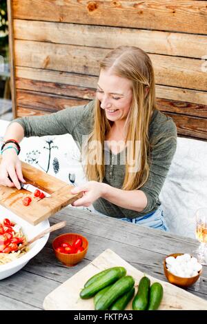 Frau scarping Tomaten in Schüssel aus Schneidebrett Stockfoto