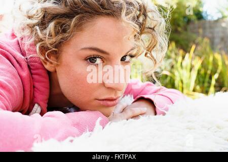 Junge Frau mit den Händen auf Kinn, Blick in die Kamera Stockfoto
