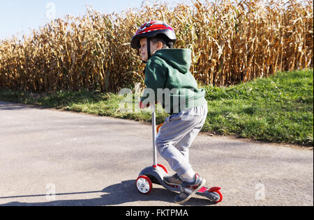 kleiner Junge eine Push-Motorroller entlang eines Pfads, ländliche Landschaft Stockfoto