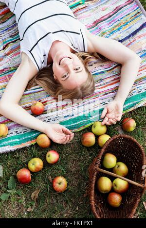 Frau liegend auf gestreiften Teppich mit Korb Äpfel Stockfoto