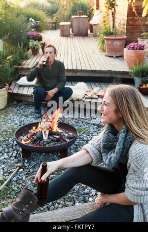 Mann und Frau von Feuerstelle mit Bier sitzen, relaxen Stockfoto