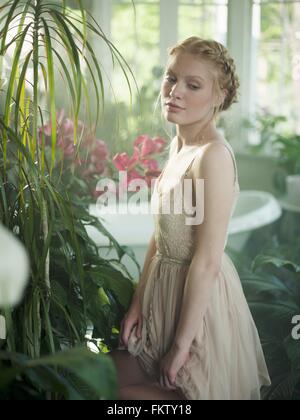 Junge Frau, im Bad voller Pflanzen Stockfoto