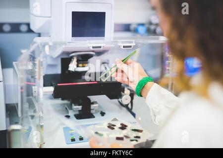 Wissenschaftlerin mit FTIR-Spektralphotometer, Dünnschicht-Probe auf Mikroskoptisch positionieren Stockfoto