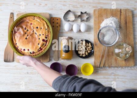Draufsicht der weiblichen Hand hob gebackenen Kuchen am Küchentisch Stockfoto