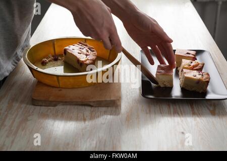 Weibliche Hände Platzierung Kuchen auf Teller am Küchentisch Stockfoto