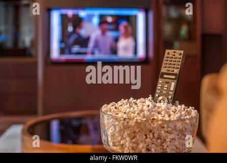 Vor dem Fernseher mit Fernbedienung und Schüssel popcorn Stockfoto