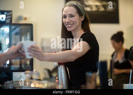 Junge Kellnerin Tasse Kaffee Café Kunden übergeben Stockfoto