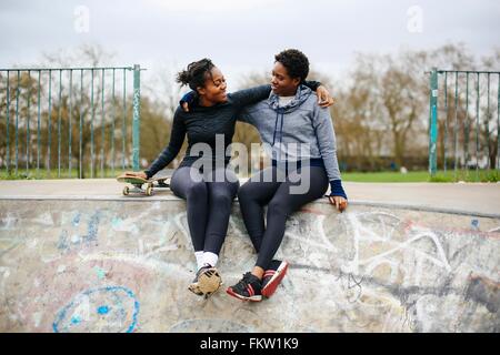 Zwei junge Skateboard Freundinnen sitzen im Skateboard-park Stockfoto