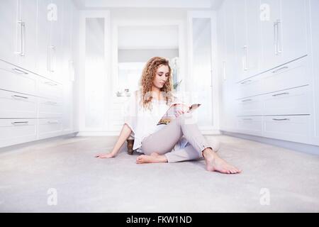 Junge Frau am Boden ein Buch im Schlafzimmer Stockfoto