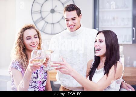 Drei junge Erwachsene Freunde machen einen weißen Wein Toast in Küche Stockfoto