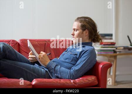Mann schreiben Hinweise auf couch Stockfoto