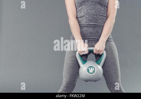 Junge Frau mit Kettlebell, grauen Hintergrund Stockfoto