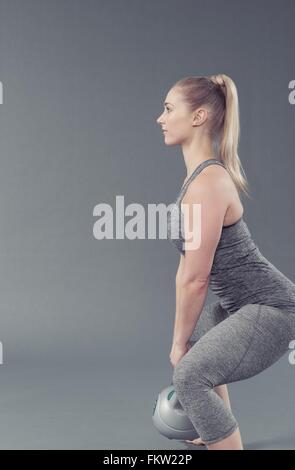 Junge Frau mit Kettlebell, grauen Hintergrund Stockfoto