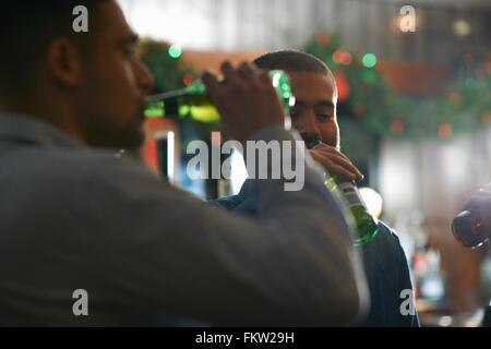 Junge Männer im Wirtshaus Bier aus Flaschen trinken Stockfoto