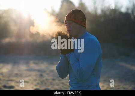 Läufer tragen Strick Mütze und Handschuhe, Hände aneinander zu reiben, kalte Atemluft Stockfoto