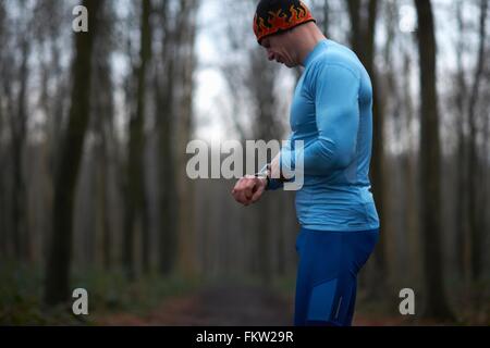 Läufer tragen stricken Hut und Spandex blickte auf Armbanduhr Stockfoto