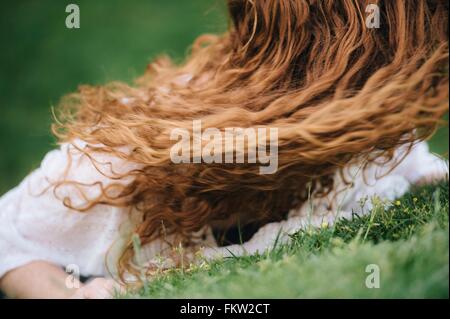Junge Frau liegt auf dem Rasen Stockfoto
